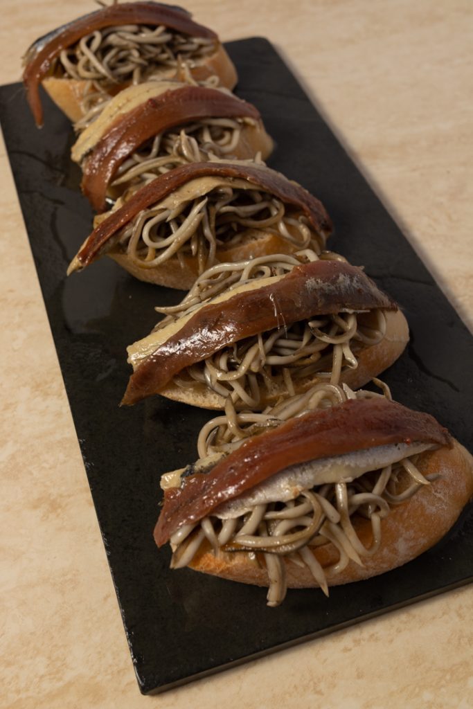 Tapa de gulas con anchoas y aceite encima de un pan Fotografo y videografo de gastronomia en Alicante
