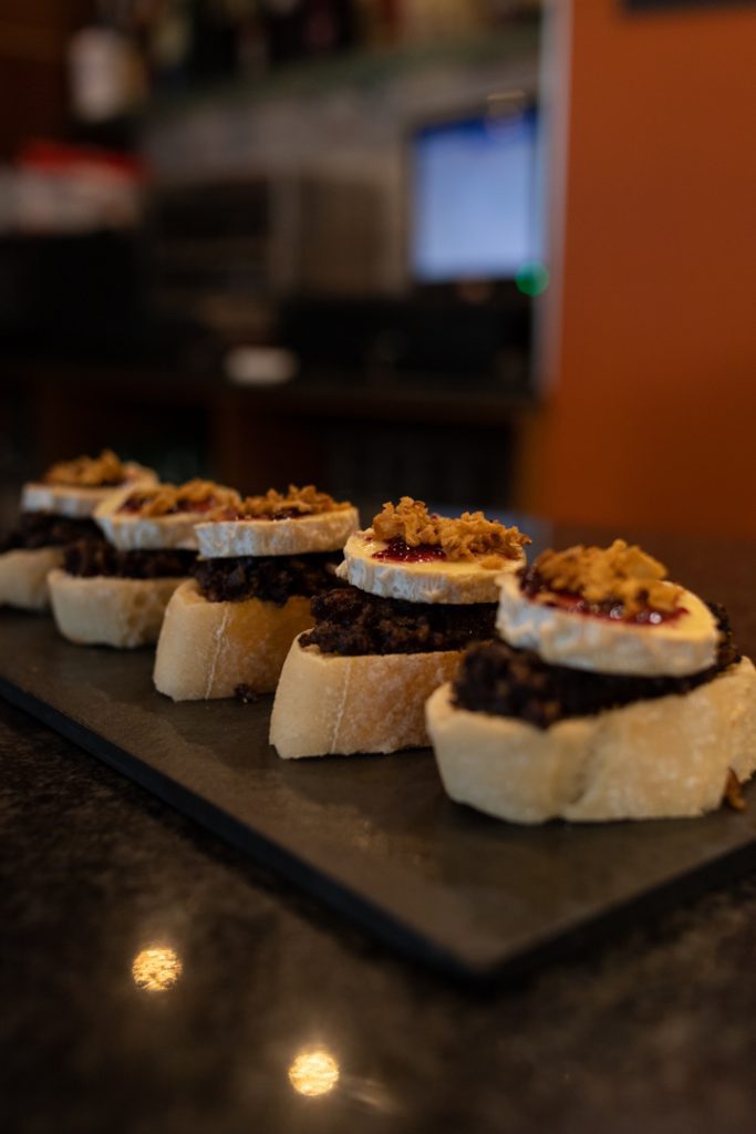 Tapa de morcilla con queso de cabra, mermelada de fresa y cebolla caramelizada encima de un pan Fotografo y videografo de gastronomia en Alicante